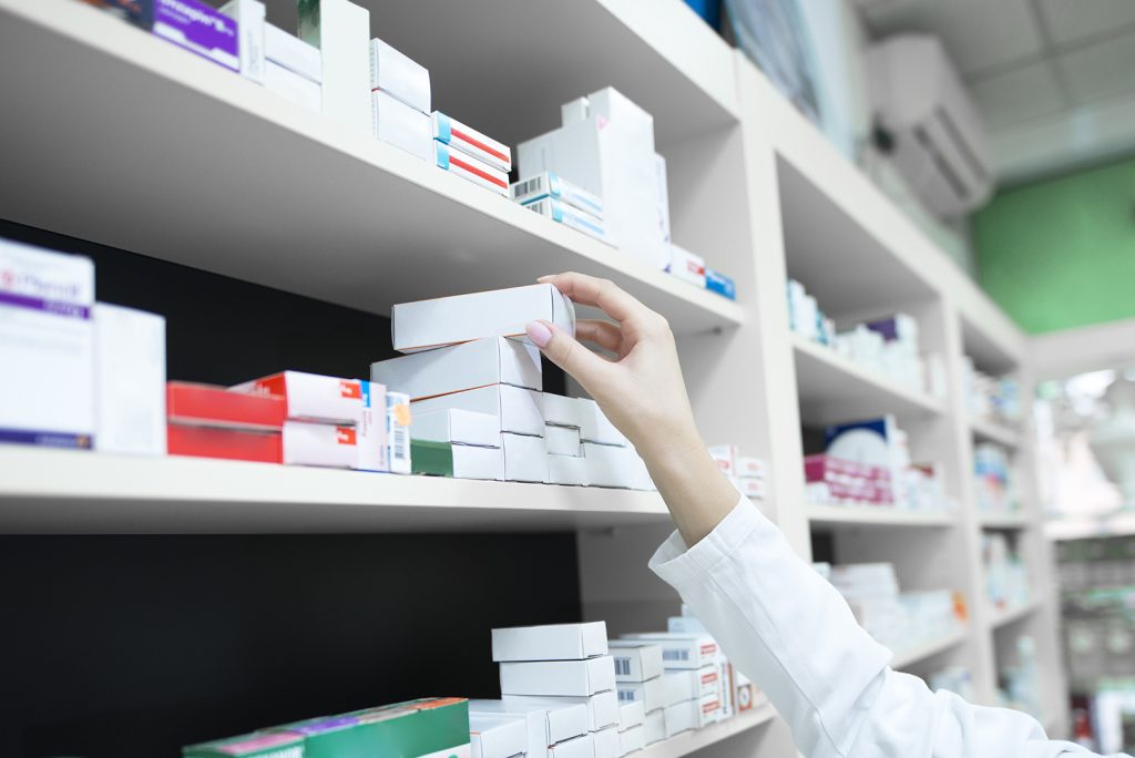 Closeup view of pharmacist hand taking medicine box from the she